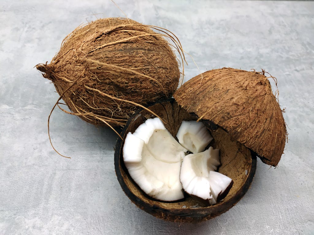 Detailed view of cracked coconut with fresh white coconut meat on a gray background.